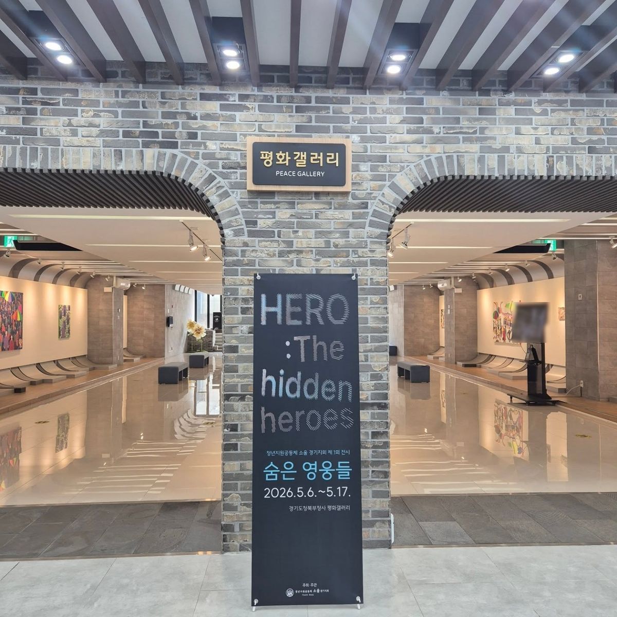 평화갤러리 입구에 세운 전시 배너. HERO : The hidden heroes, 숨은 영웅들, 2026년 5월 6일 ~ 17일