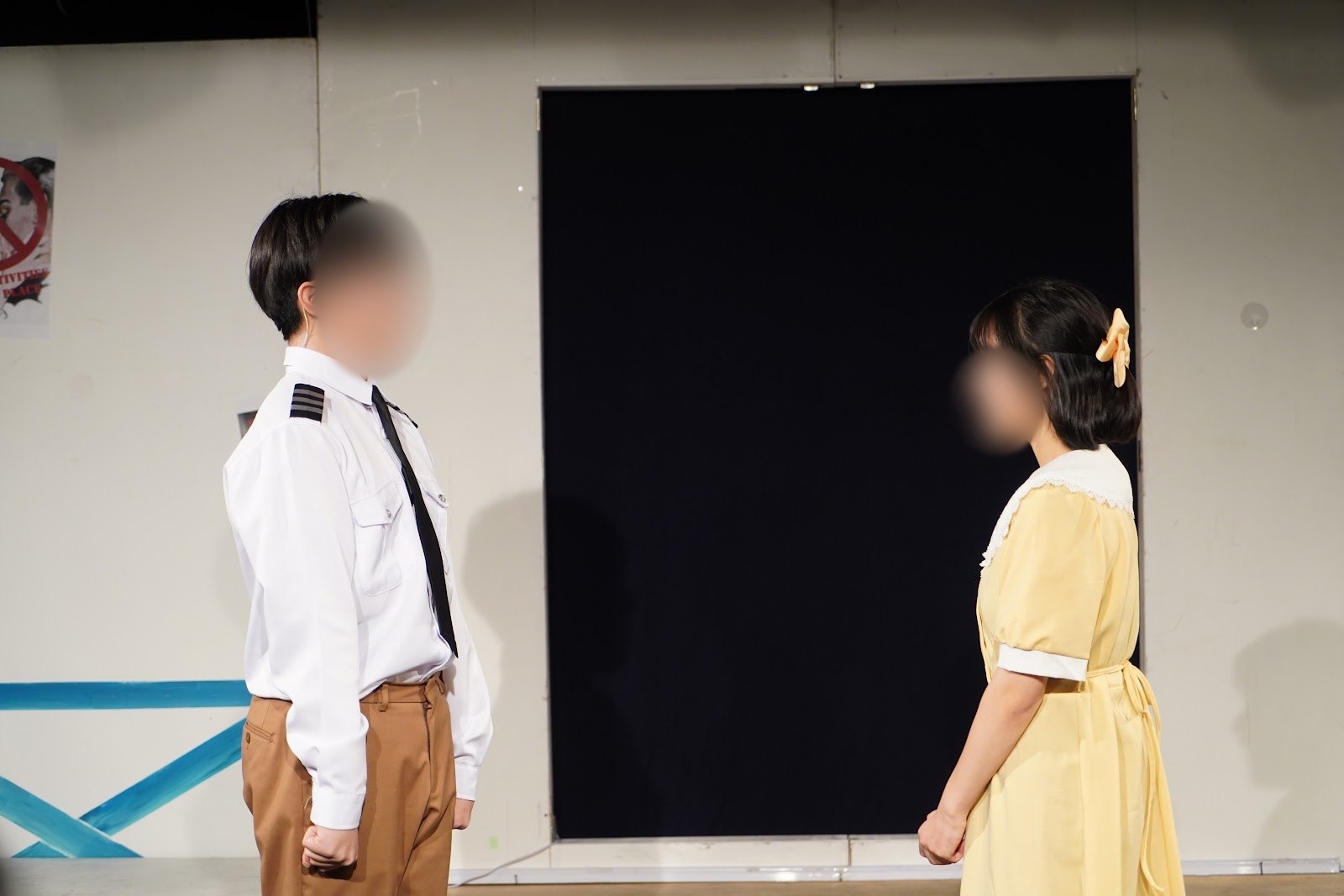 제복을 입은 배우와 노란 원피스를 입은 배우가 마주 선 장면입니다.